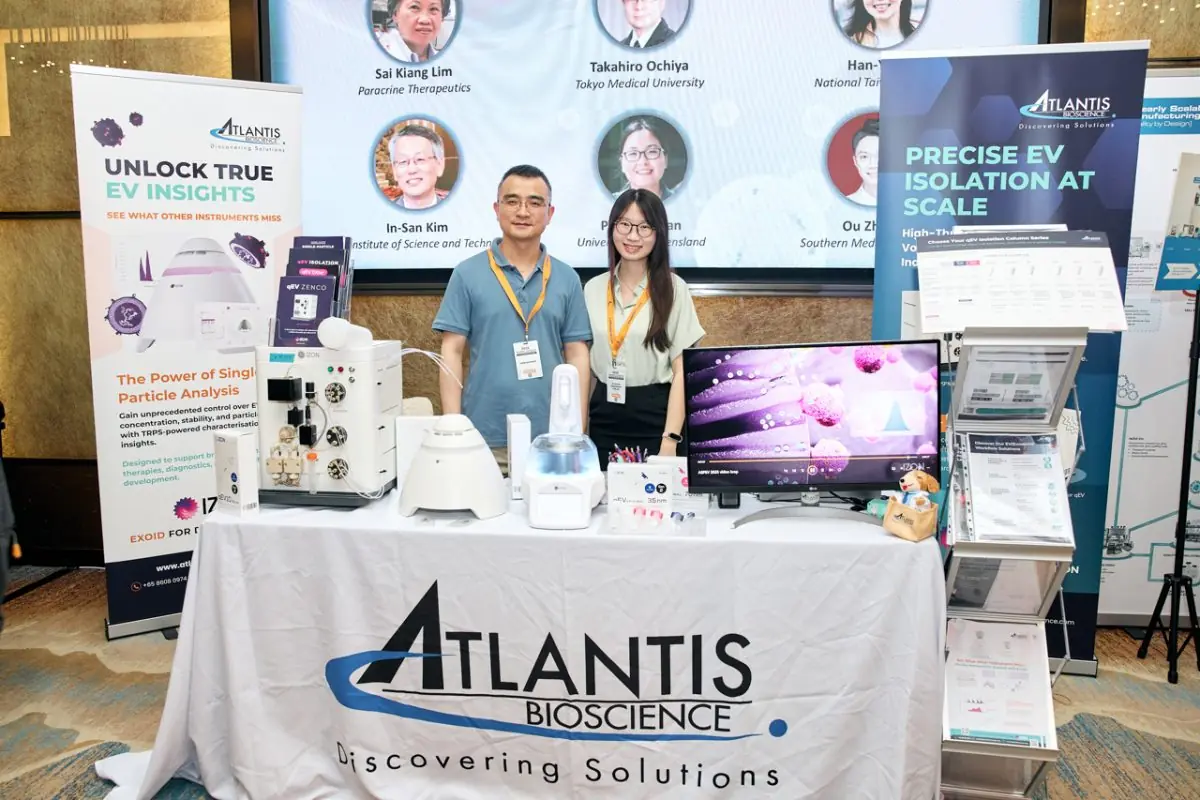 Group photo of representatives from Atlantis Bioscience (right) and Izon Science (left) at the ASPEV 2025 exhibition booth.